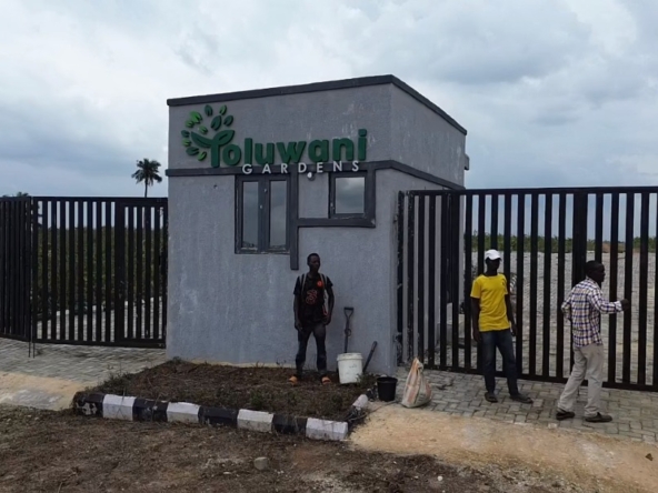 Entrance to Oluwani Gardens with three people outside.