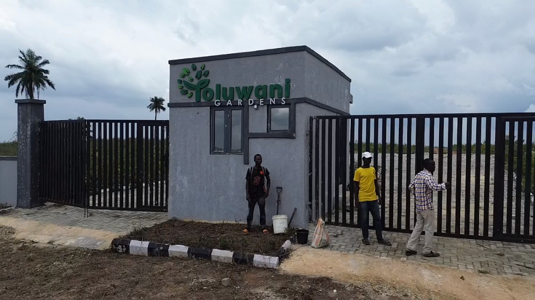 Entrance to Oluwani Gardens with three people outside.
